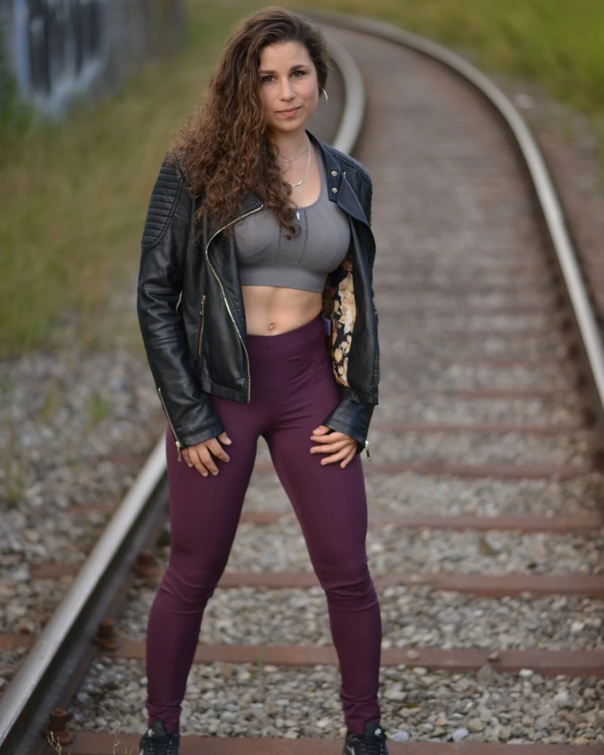 Model mit schwarzer Lederjacke auf geschwungenen Bahngleisen