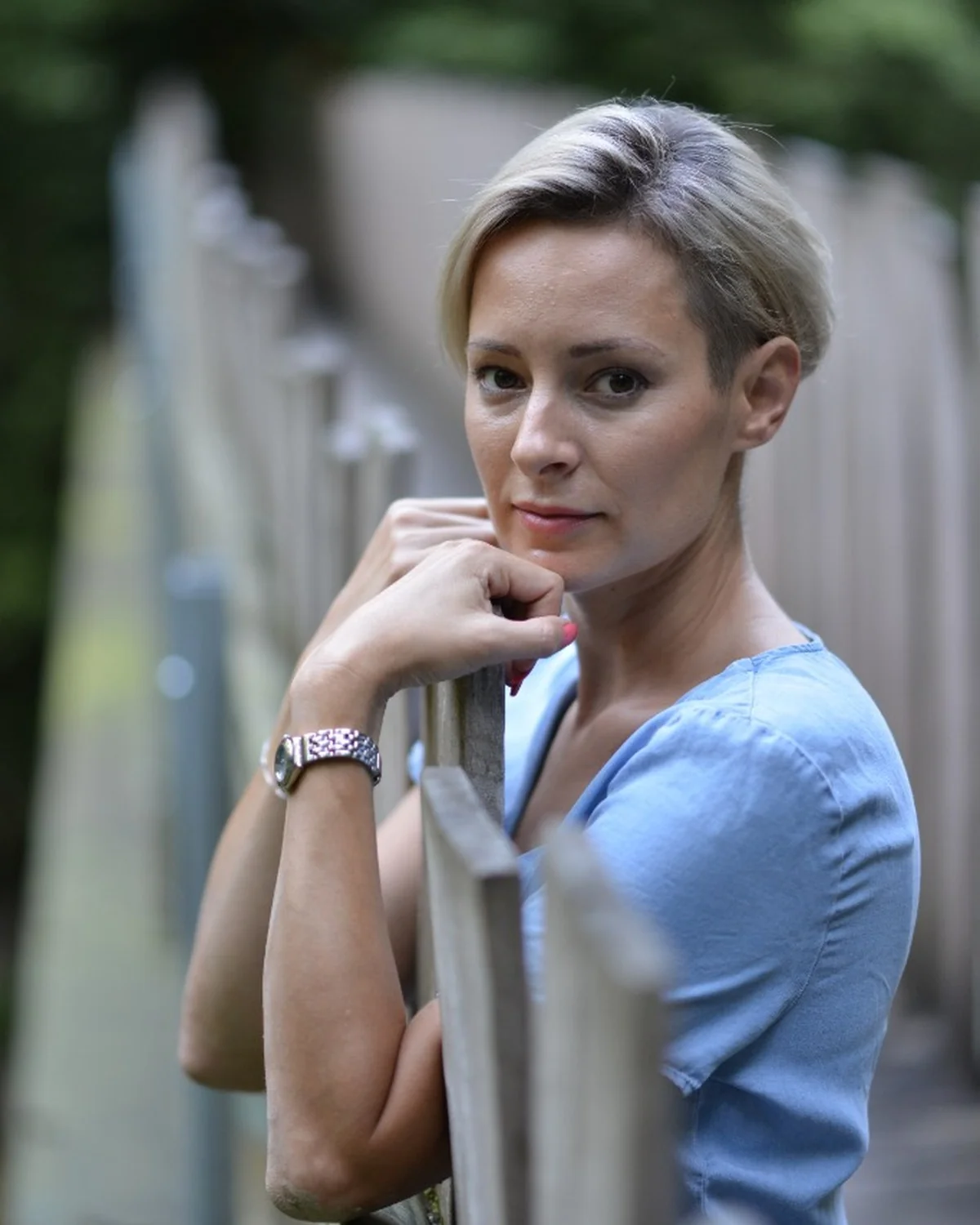 Porträt blondes Model am Holzgeländer mit weichem Bokeh