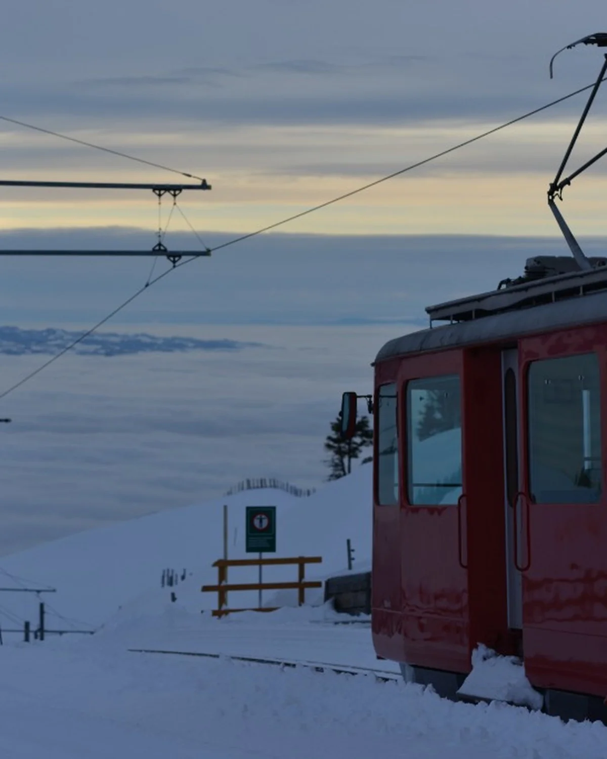 Rote Vitznau-Rigi-Bahn im Schnee über dem Nebelmeer bei Sonnenuntergang